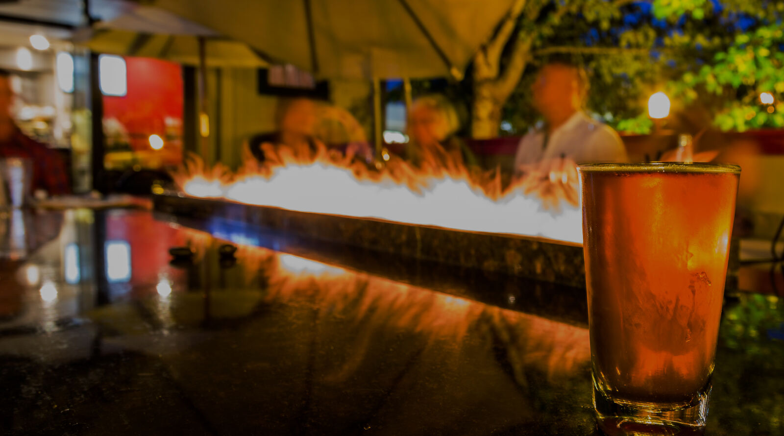Fireside flames behind a glowing cocktail at The Fireside Grill